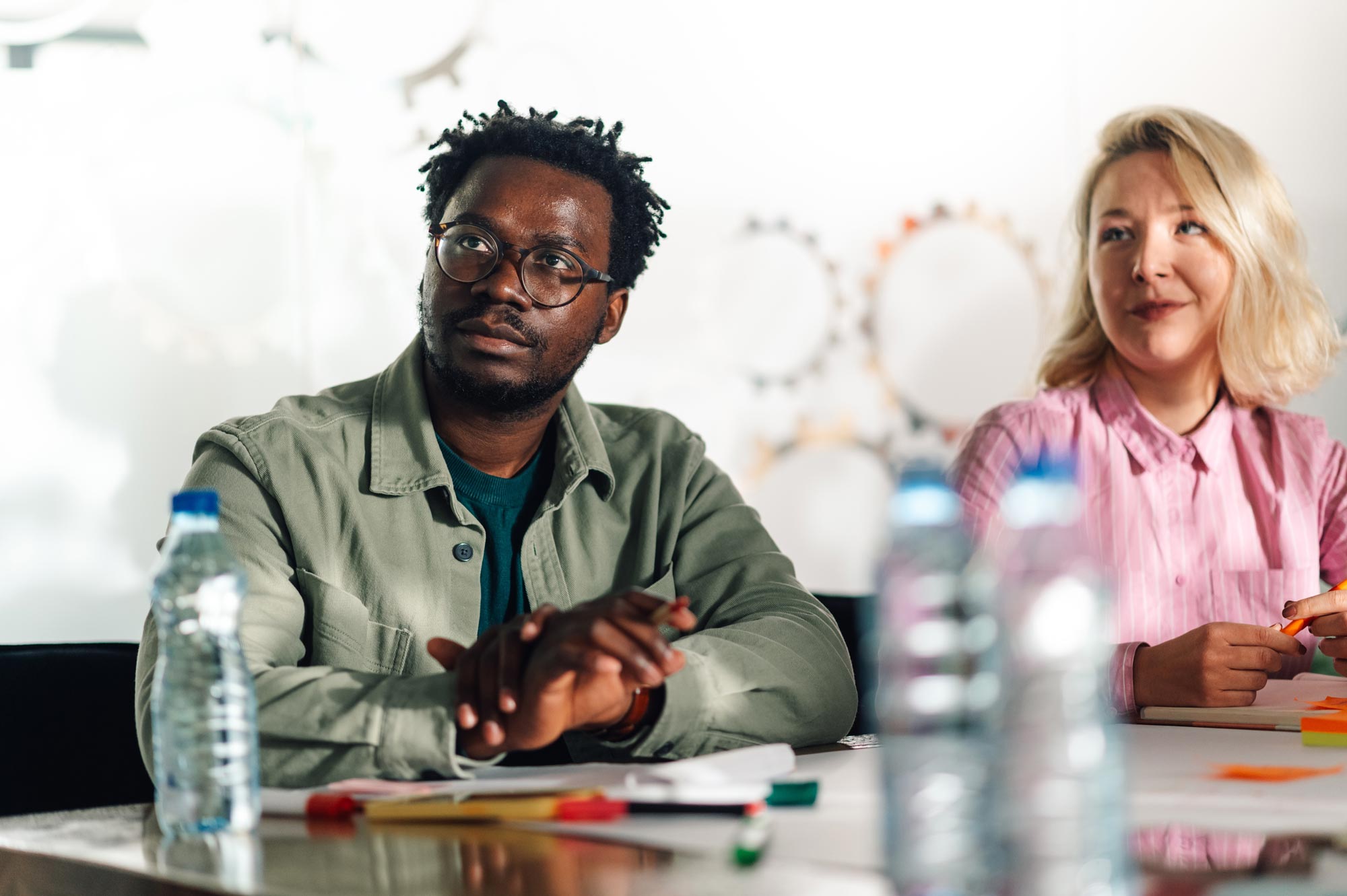 Two business colleagues are actively listening and participating in a meeting, demonstrating teamwork and focus in a professional environment